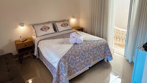 Una cama bien hecha con una colcha estampada, una mesita de noche con un control remoto y un aire acondicionado instalado en la pared.