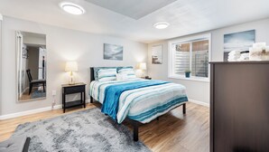 A bedroom with a bed, bedside lamps, a mirror, a dresser, and a window with blinds. - 3 bed 1 bath W. Bannock Beauty (Boise)
