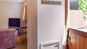 Una habitación con televisión, un sofá estampado, una puerta de madera y un grifo.