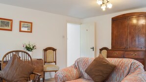 Una sala de estar con un sofá, un sillón mecedora, un aparador de madera y una mesa de comedor con sillas.