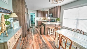 Eine moderne Küche mit Holzboden, einer zentralen Kochinsel und einem Essbereich mit weißem Tisch und Holzstühlen.