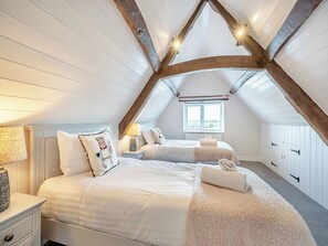 Una camera da letto con due letti, una finestra e un soffitto a falde con travi a vista.