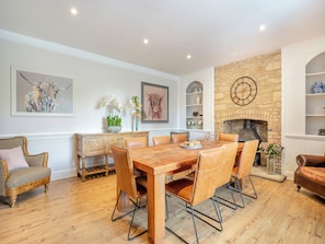 A dining area with a wooden table and chairs, a fireplace, and decorative items on the walls.