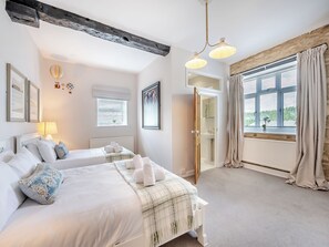 Ein Schlafzimmer mit zwei Betten, einem Fenster mit Vorhängen, einem Heizkörper und einer Deckenleuchte.