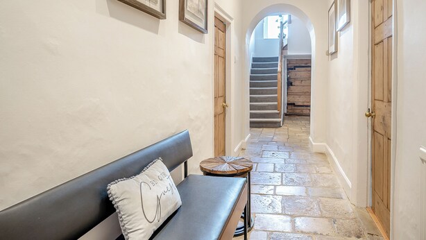 Un couloir avec un banc, des œuvres d’art encadrées, des portes en bois et un escalier.