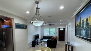 A modern kitchen with a dining area, a large window, and a cityscape painting.