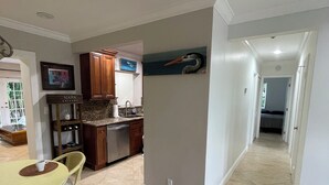 A modern kitchen with wooden cabinets, a dining area with a table and chairs, and a hallway leading to other rooms.