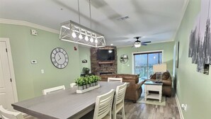 A dining area with a rectangular table, white chairs, and a modern pendant light. - Updated~ Legacy Manor, 2br, 2ba,  Downtown Gatlinburg, Walking Distance to all (Gatlinburg)