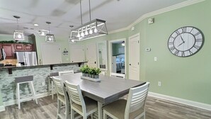 A modern kitchen with a dining area, featuring a large clock on the wall and pendant lights above the table. - Updated~ Legacy Manor, 2br, 2ba,  Downtown Gatlinburg, Walking Distance to all (Gatlinburg)