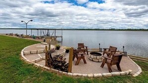 A lakeside patio with outdoor seating and a fire pit.