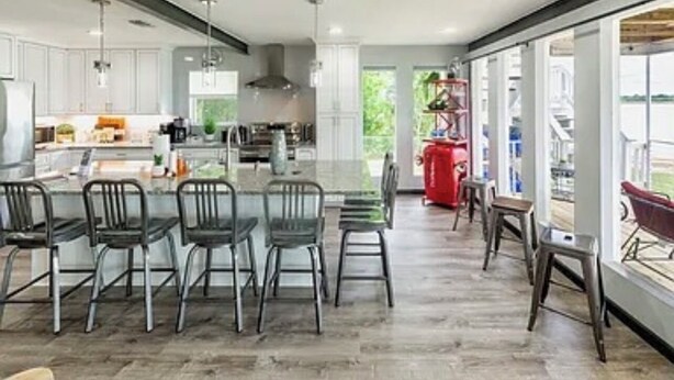 A spacious kitchen with a central island, bar stools, and a view of the outdoors.