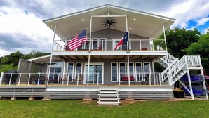 A two-story building with a balcony, a staircase, and a flagpole with two flags.