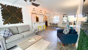 A modern living room with a grey sofa, a blue armchair, and a coffee table. There is a decorative wall piece above the sofa and a mirror above the armchair. - Cozy 1-bedroom, resort style condo. w/ WiFi, AC in beautiful Scottsdale (Scottsdale)