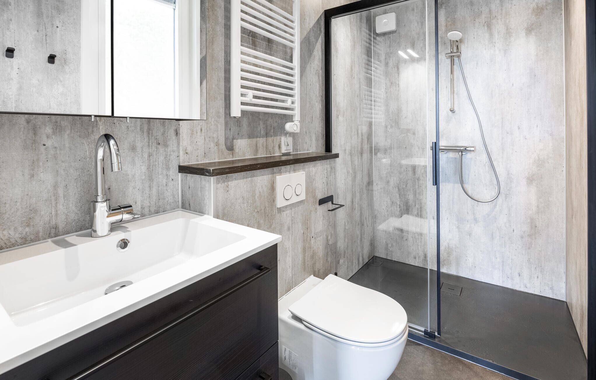 Ein modernes Badezimmer mit einem weißen Waschbecken, einer Toilette und einer Duschkabine.