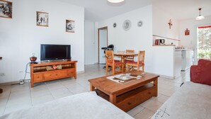 Ein Wohnzimmer mit Fernseher, Holzmöbeln, Essbereich und Küche.