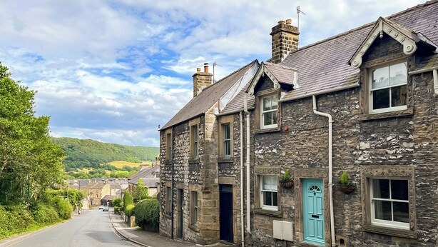 A stone building with a blue door, a chimney, and a window with a white frame. - 3 bedroom accommodation in Bakewell (Bakewell)