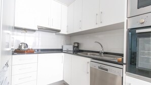 A modern kitchen with white cabinets, a stainless steel sink, a coffee maker, and a dishwasher. - 097 - Club Náutico 012 - comfortHOLIDAYS (Santa Pola)