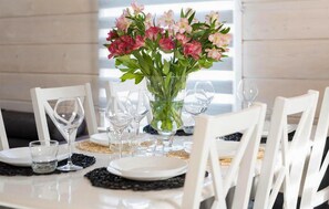 Enjoy a beautifully set table with white chairs, a vase with fresh flowers, and elegant glassware.
