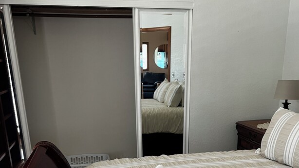 A hotel room with a bed, a nightstand, a lamp, and a mirror reflecting the room.