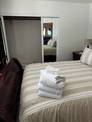 Una habitación de hotel con una cama, una mesita de noche, una lámpara y un espejo que refleja la habitación.