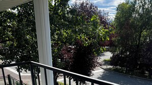 A balcony with a view of a street and trees.
