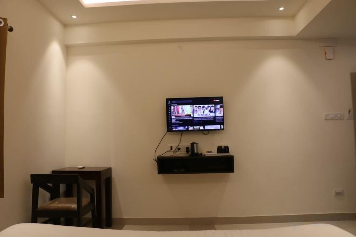 Une chambre d’hôtel avec un lit, un téléviseur fixé au mur, une petite table et une chaise.