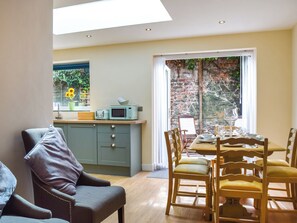 A modern kitchen with a skylight, a dining area with wooden chairs, and a view of a brick wall through a window.