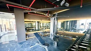 A gym with exercise equipment, benches, and dumbbells. - Luxury 1BR Near Miracle Garden |Uni Estate Supreme (Arjan)