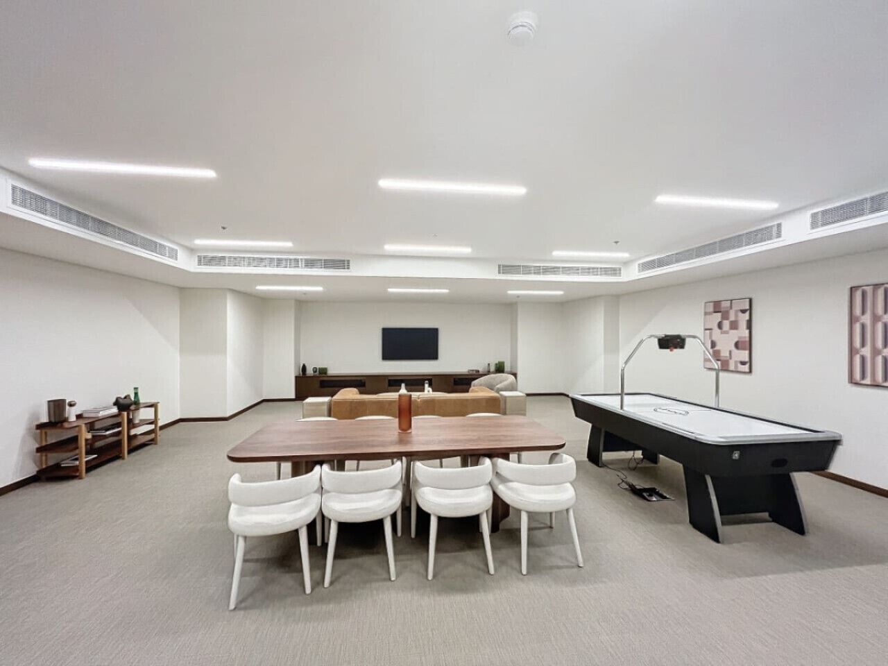 Une salle de conférence avec une longue table, six chaises, un billard et un téléviseur à écran plat fixé au mur.