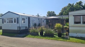 Ein Mobilheim mit eingezäuntem Garten und Blumentöpfen.