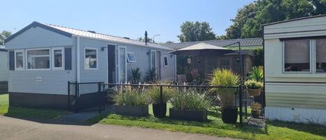 A mobile home with a fenced yard and potted plants.