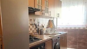 A compact kitchen with a refrigerator, stove, oven, and washing machine. - Apartment 5 minutes' walk from the beach (martil)