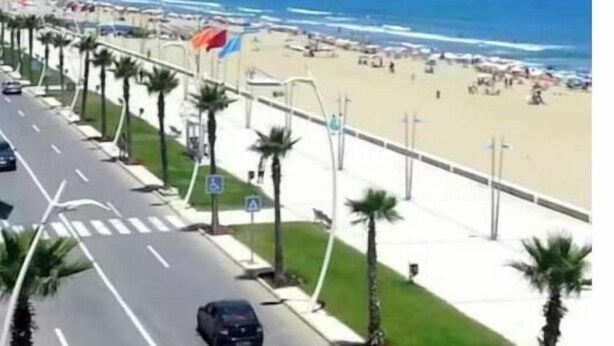 A coastal road with palm trees, a beach, and a clear blue sky. - Apartment 5 minutes' walk from the beach (martil)