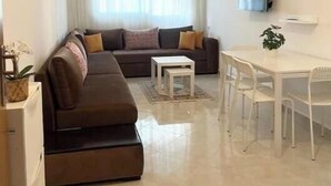 A modern living room with a sofa, coffee table, dining table, and chairs. - Apartment 5 minutes' walk from the beach (martil)