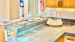 A kitchen with a granite countertop, white cabinets, and a pink plush toy hanging on the wall. - Cozy, Quiet, Bothell River House (Bothell)