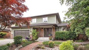 A two-story house with a front garage, a brick facade, and a landscaped front yard with a pathway and rocks. - Cozy, Quiet, Bothell River House (Bothell)