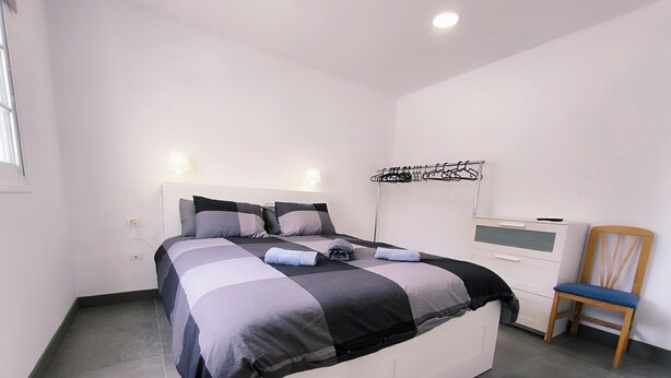 Un dormitorio moderno con una cama grande, televisión y una silla.