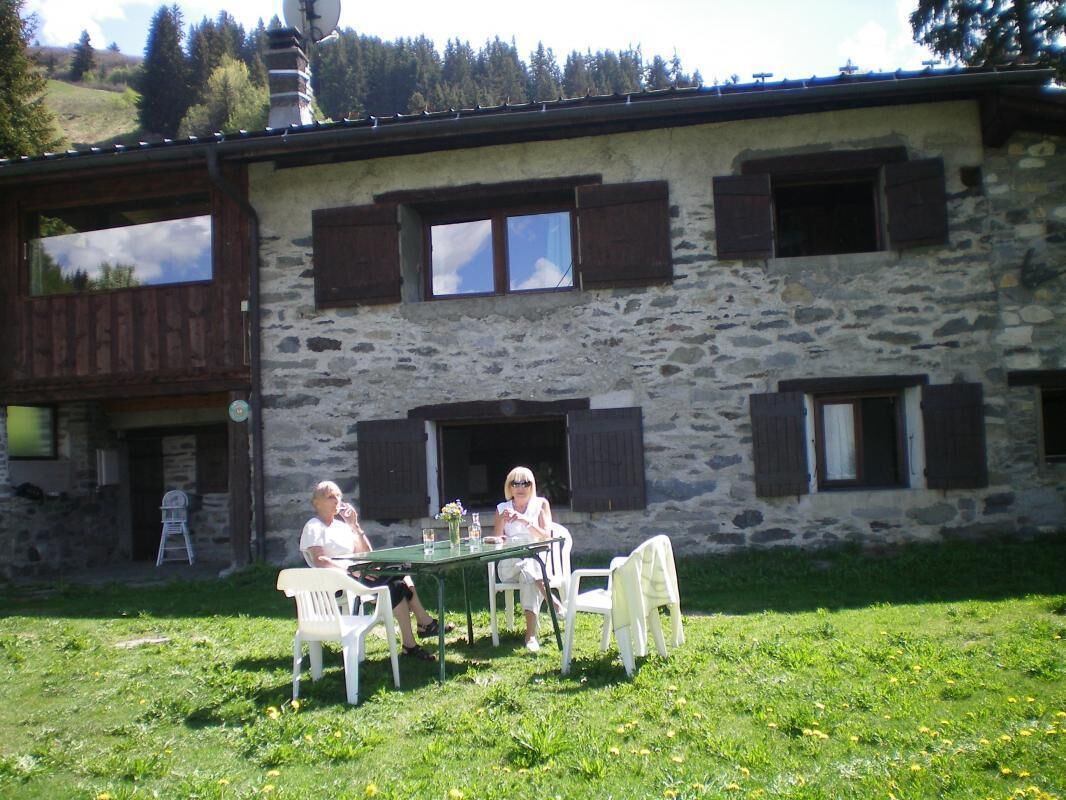 Ein Steinhaus mit rustikalem Äußeren, einem Esstisch mit Stühlen und freiem Blick auf die umliegende Natur.