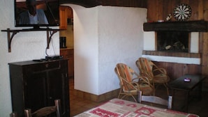 Un salon confortable avec un téléviseur, des meubles en bois et un jeu de fléchettes.