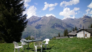 Une table à manger avec des chaises, installée dans un espace verdoyant avec vue sur la montagne.