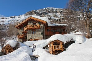 Um edifício de pedra com varandas de madeira e telhado coberto de neve.