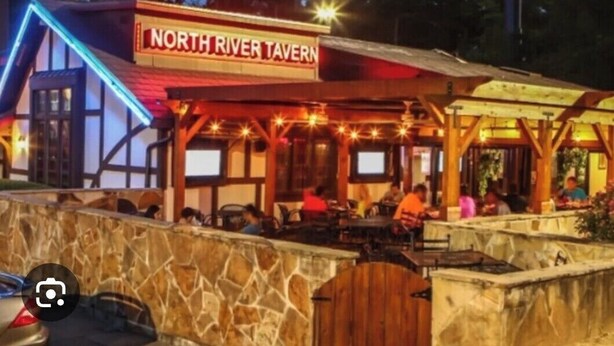 North River Tavern mit Außenbestuhlung und einer Steinmauer.