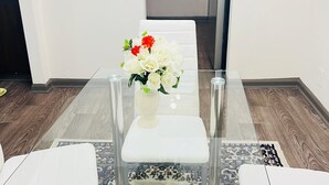Eine moderne Küche mit einem Edelstahl-Kühlschrank, einem weißen Esstisch mit Glasplatte und einer Blumenvase.
