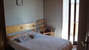 Ein Schlafzimmer mit einem hölzernen Bett, einem Sessel und einem Fenster mit Vorhängen.