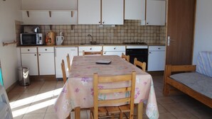 Eine kleine Küche mit Esstisch, Stühlen, Mikrowelle, Kaffeemaschine und Geschirrspüler.