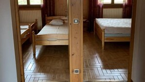 Ein Zimmer mit Holzboden, zwei Betten, einem Heizkörper und einem fenster mit Vorhängen.