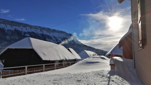 A snow-covered mountain village with traditional houses, a wooden fence, and a clear sky. - ECOLE A GITER - NID D'AIGLE (SAINT FRANCOIS DE SALES)