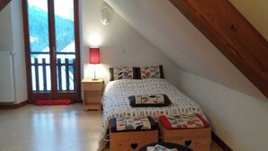 A bedroom with a bed, bedside tables, a lamp, and a view of the outdoors. - ECOLE A GITER - NID D'AIGLE (SAINT FRANCOIS DE SALES)