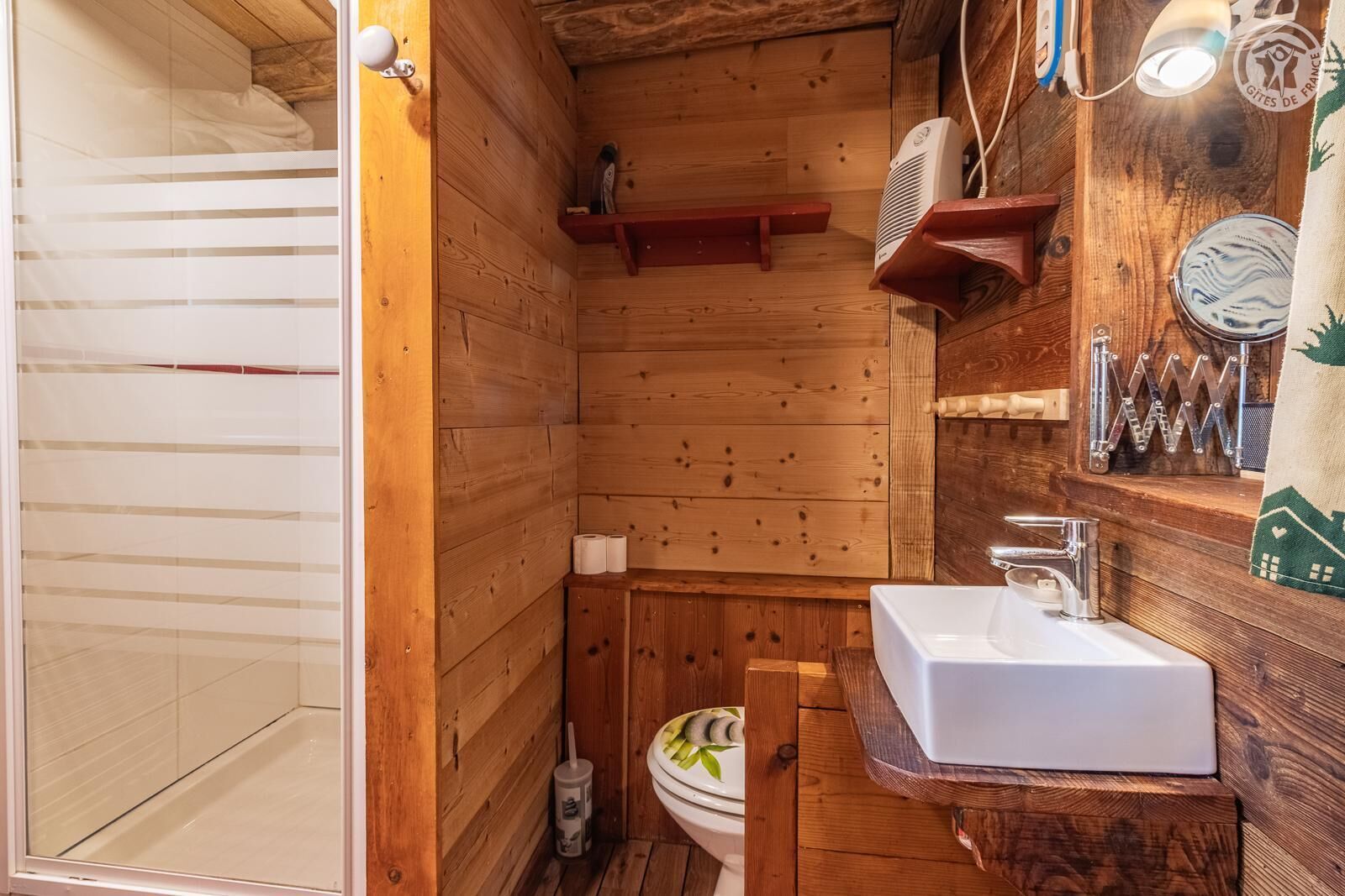 Een houten badkamer met een douche, toilet en wastafel.