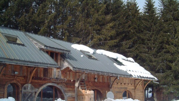Eine Holzhütte mit Metallbedachung, umgeben von Schnee und Kiefern.